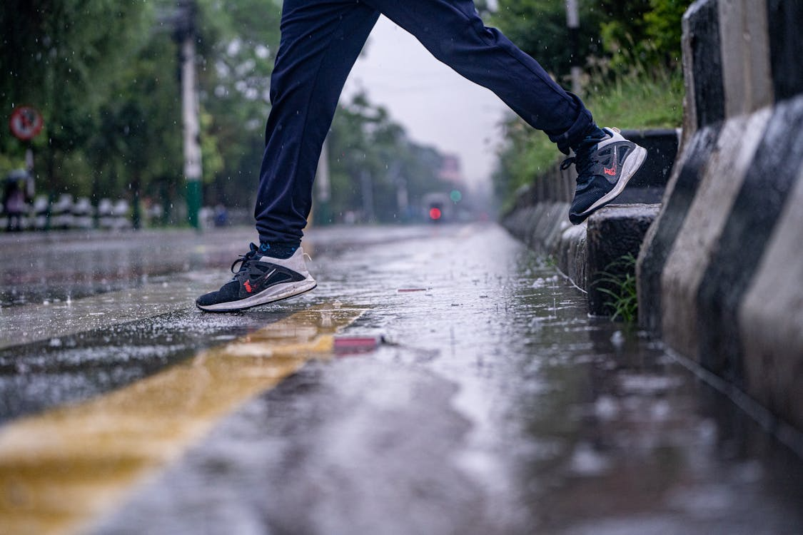 What to wear running in rain — runner in waterproof jacket on wet urban road at dusk