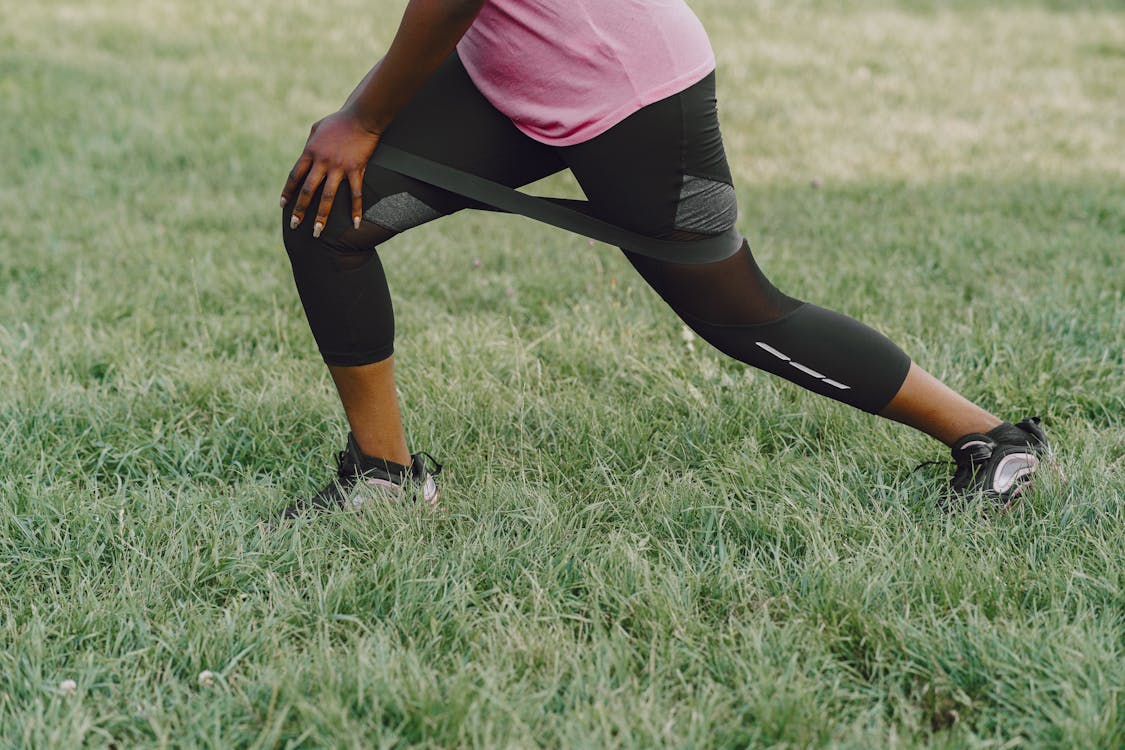 IT band pain runners fix — runner stretching hip and glute on trail